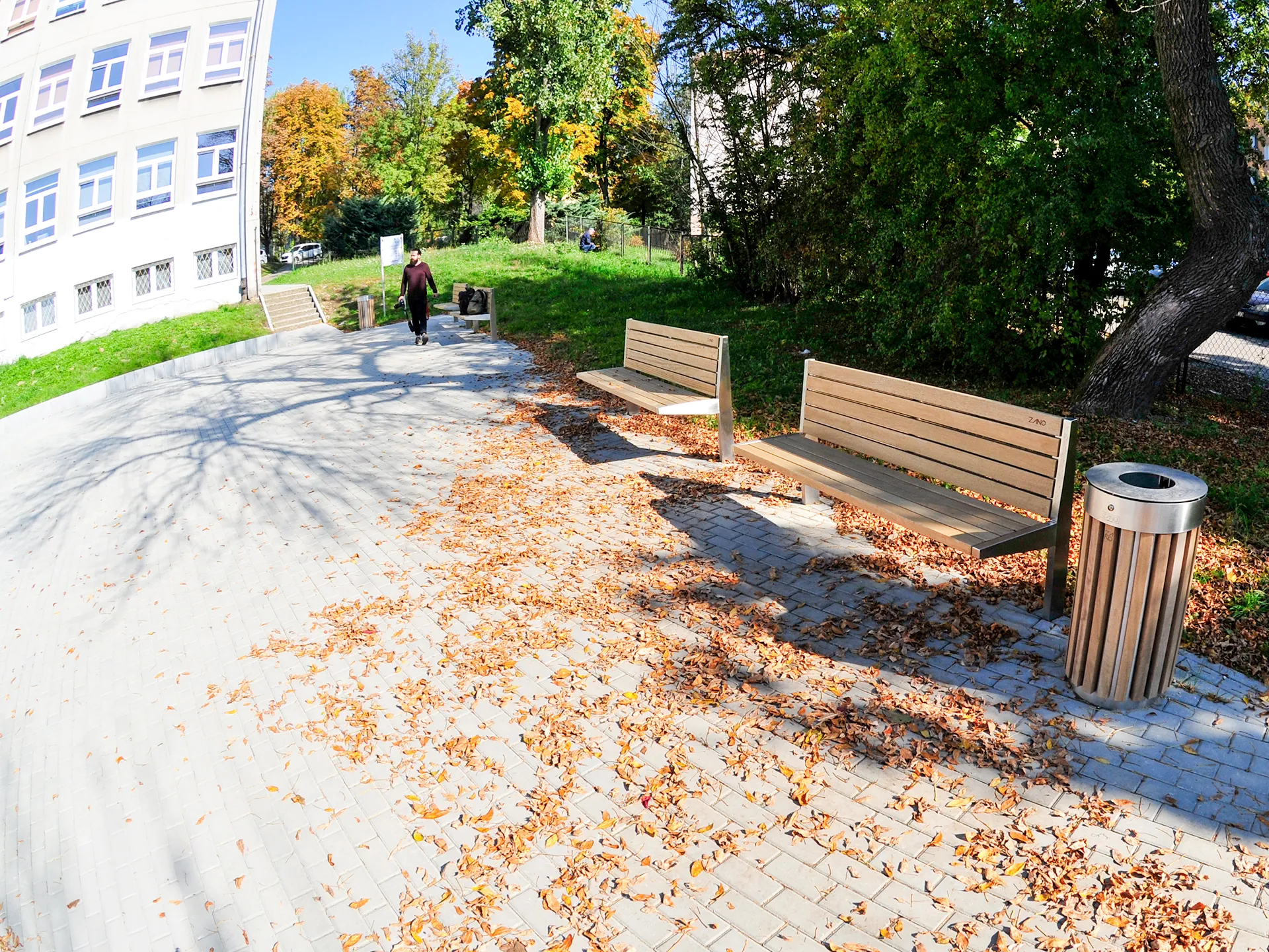 Šiuolaikiškas miesto suoliukas su medine sėdyne bei atlošu ant plieninio rėmo ir apvalus šiukšlių konteineris